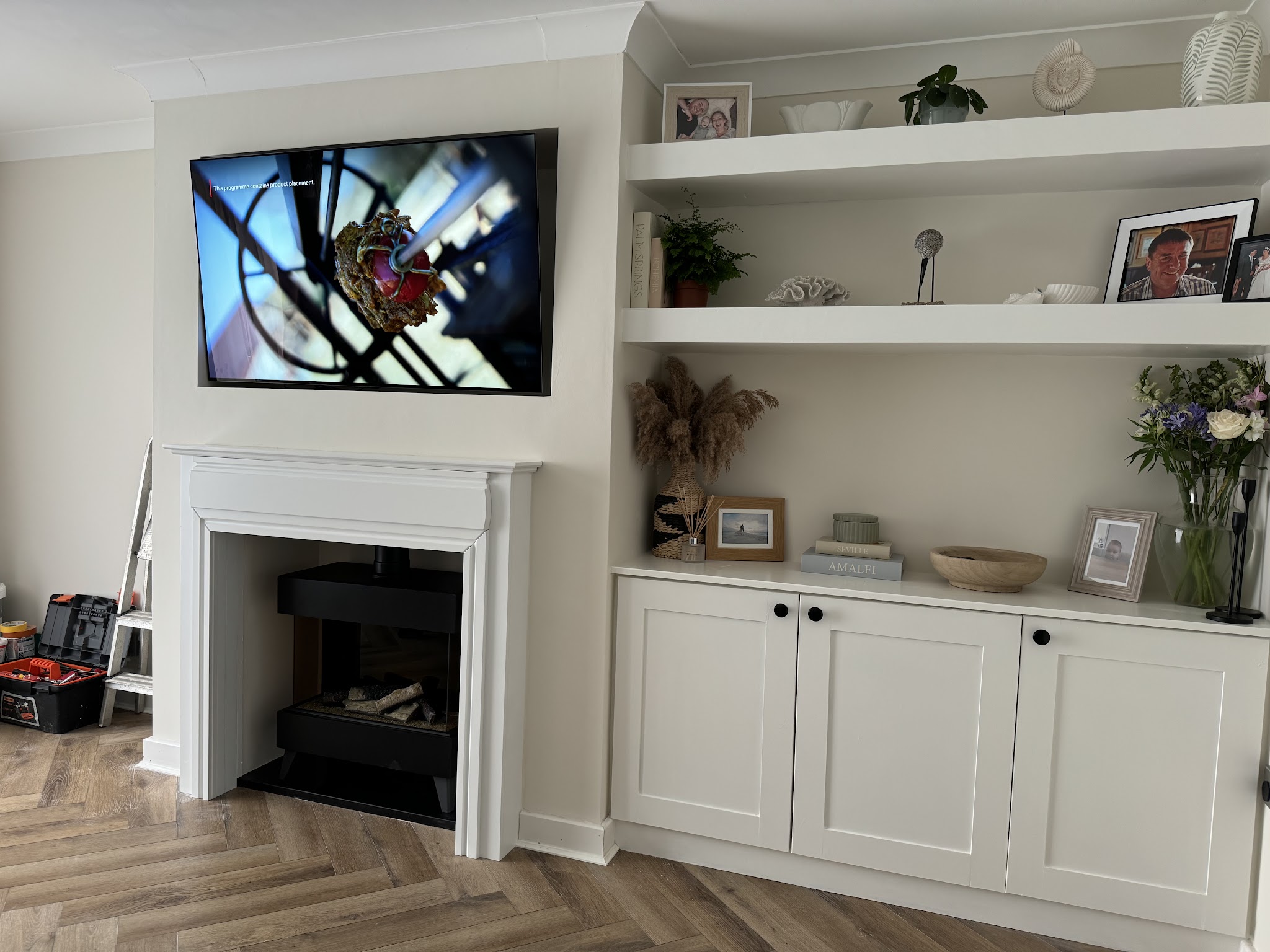 White alcove cupboards and floating shelves either side of a fireplace