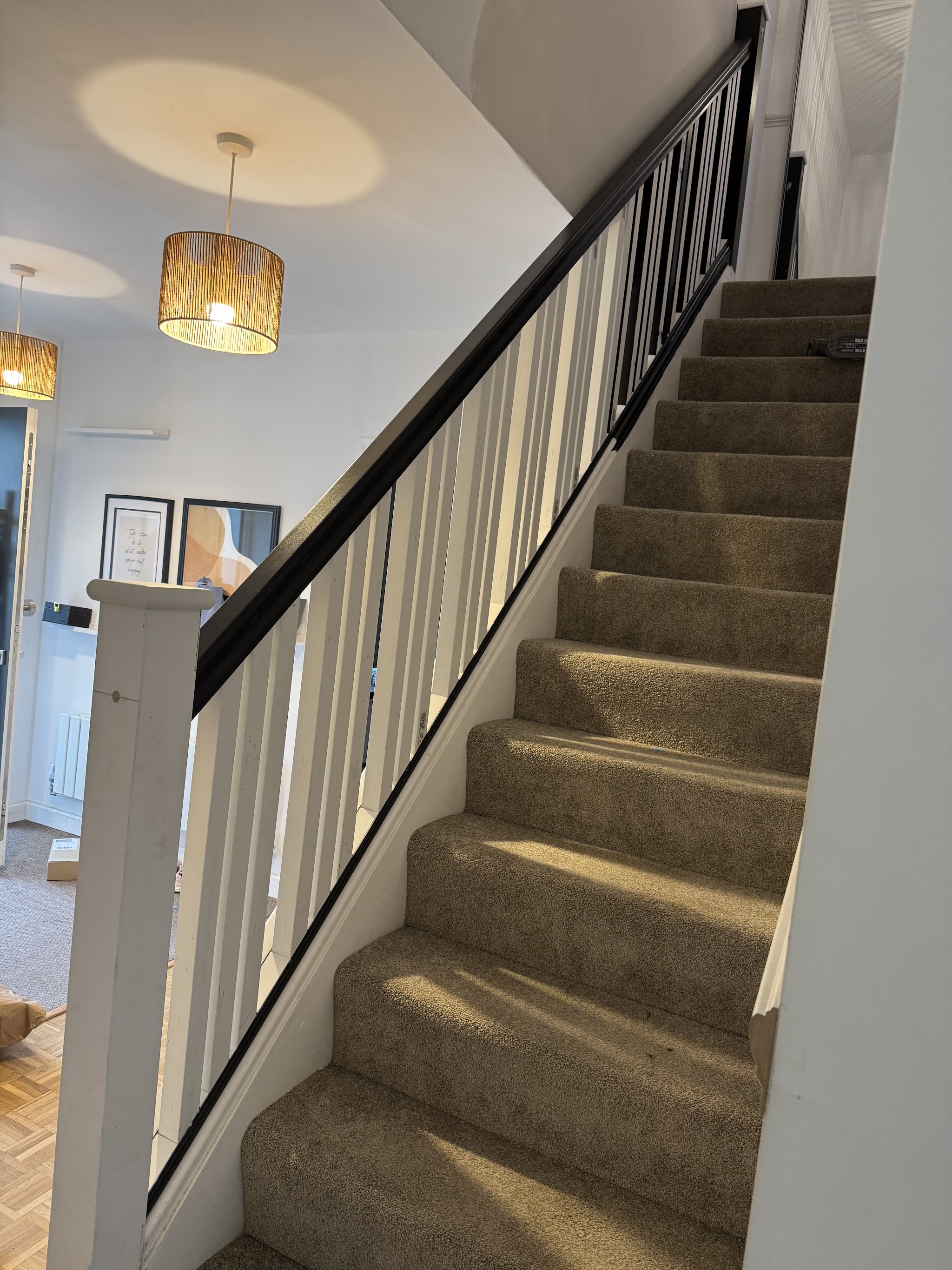 Staircase with white spindles and a black handrail